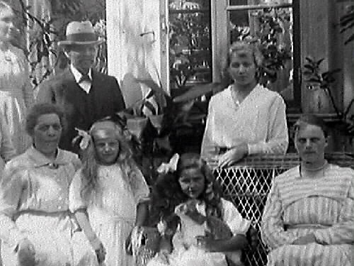Gruppbild av människor utanför en villa. Möbelhandlare C J Carlsson beställde bilden och är troligen själv med.