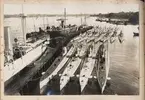 Bilden visar en del av den tyska ubåtsflottan under Första världskriget som ligger förtöjt vid en brygga i hamnen.