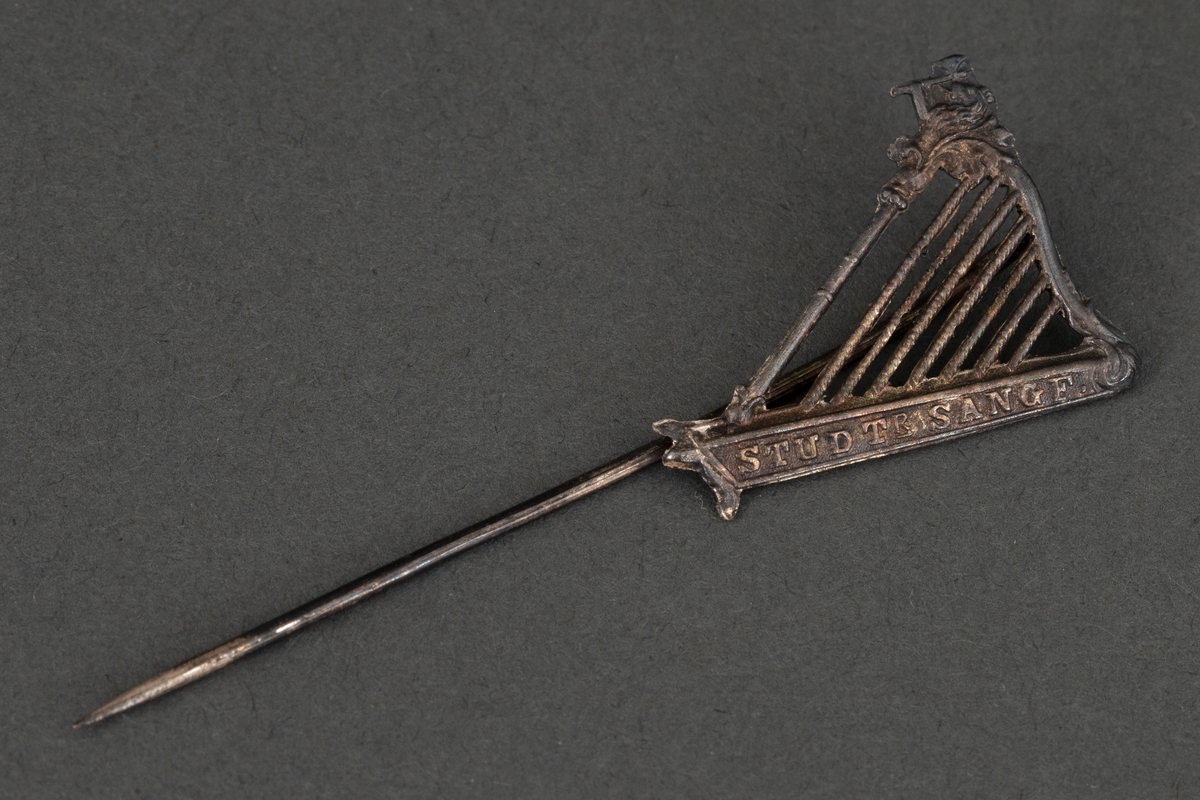 Medlemsnål for Studentersangforeningen Oslo. Harpeformet hvitt metall.