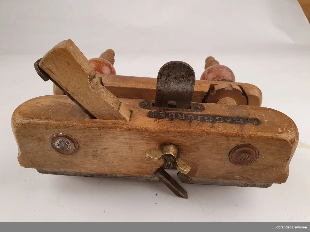 Ploghøvel, stillbar i høyde og bredde. Justeringsskruer i tre. 
Fabrikkprodusert; merket Joh-weiss.
Svimerket; J.m byggjordet, to ulike stempeltyper, 3 ulike plasser på høvelstokken.
Tilhørende 2 ekstra høvelstål. LT-03561, 01 og 02.