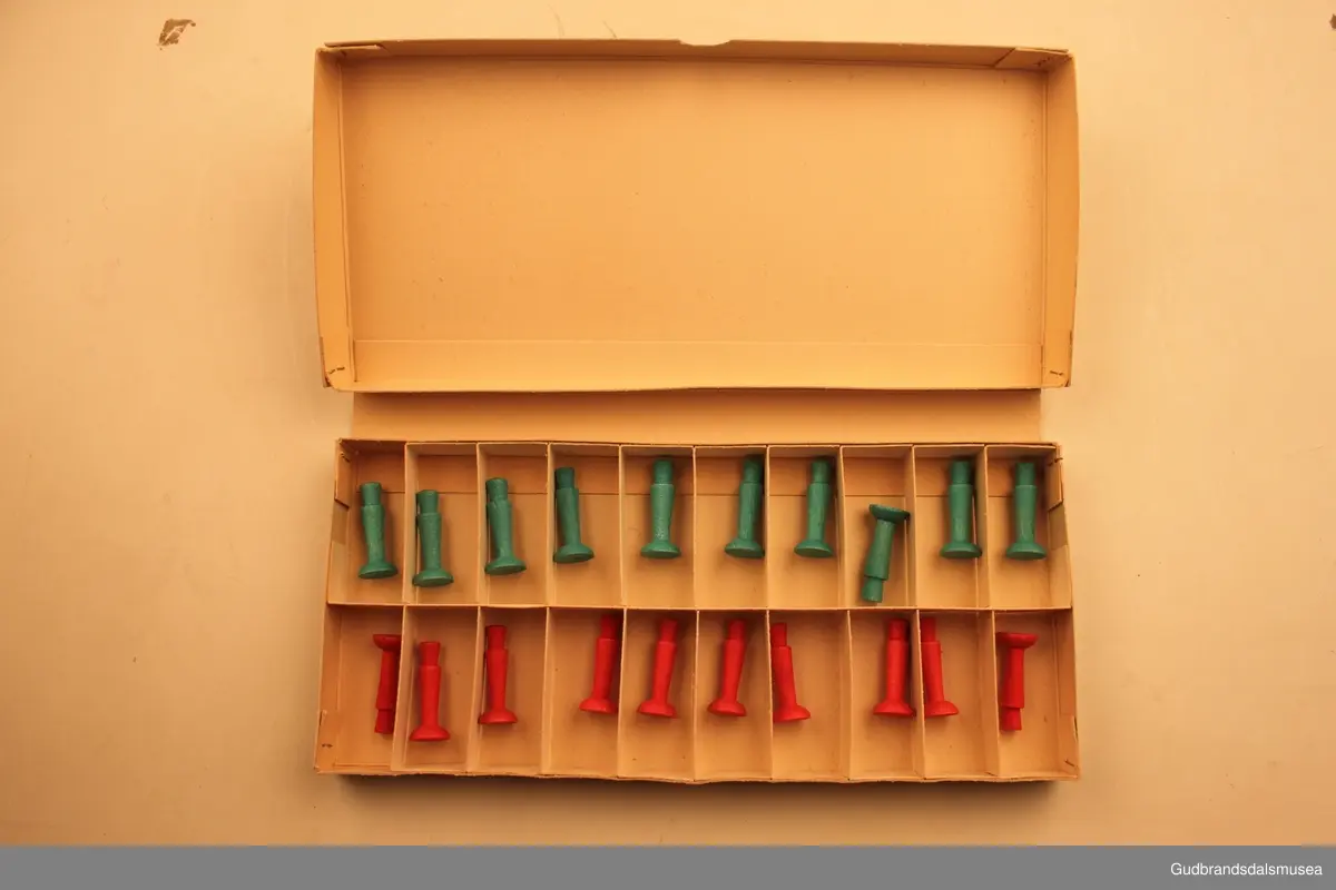 Brettspill fra ca 1940-1950 i orginaleske av papp. Spillet heter "Pel`tong", og går ut på å få fem egne brikker etterhverandre (5på rad).
Spillesken inneholder et spillebrett, som også danner esken sammenbrettet.Sammenbrettet stikkes dette inn i et fotreal av papp med logoen til spillet påtrykt. Det forhøyede spillbrettet har 20 små rom, til 10 røde spillbrikker og 10 grønne spillbrikker. Spillbrikkene er 4cm høye, dreid i tre, og skal ifølge trykk på fremsiden av esken forestille soldater. Et slags krigsspill. Eget lite hefte med spilleregler ligger i esken.
Usikker på produsent, men står merket" Kvalitetsmerke Sertifikat for spill og leker" og "Patent anm. mønster- besk." på esken.