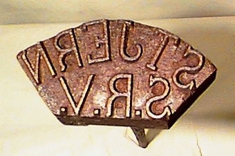 Rundstång som i övre änden är böjd till ett ovalt handtag, och i nedre änden har en märkdel i form av ett gjutet metallstycke med tre räta sidor och en böjd. I botten av metallstycket finns en spegelvänd text i relief "STJERN S.R.V."