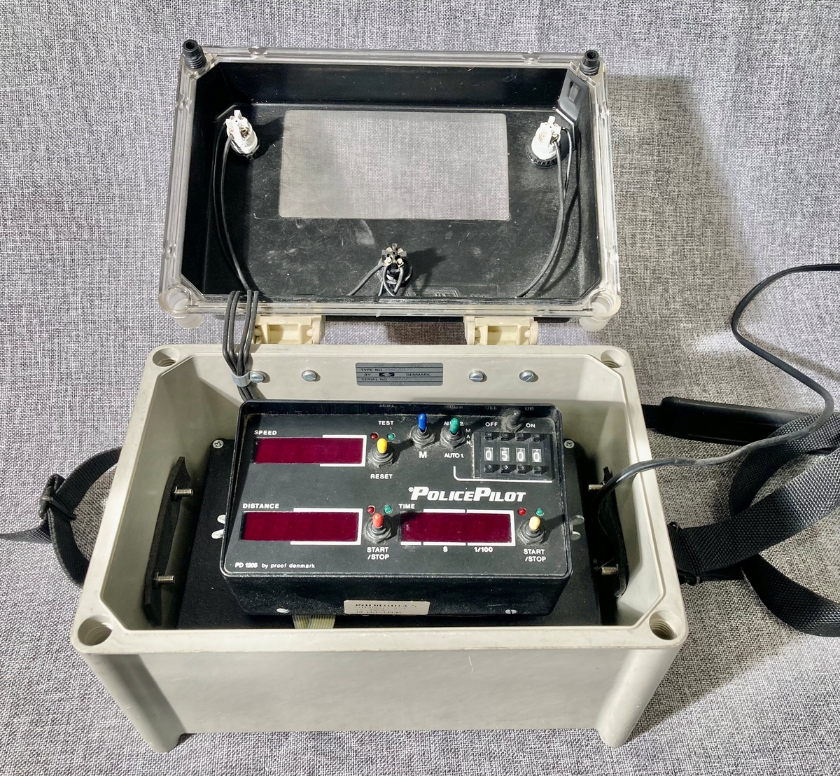 Bærbar politiradio i oppbevaringskasse med bærestropp.
