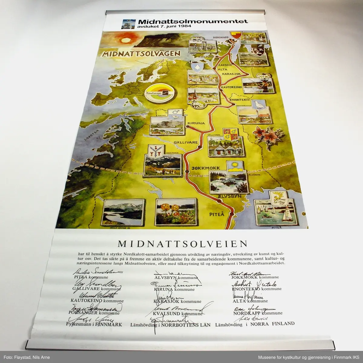 En plakat (rollup) uten etui. Plakaten er laget i forbindelse med avdukingen av Midnattsolveien monumentet. 

Øverst på plakaten er det trykt et lite bilde av Midnattsolmonumentet og tittel "Midnattsolmonumentet avduket 7. juni1984".

Rett under tittelen er det trykkt et stort kartbilde over midnattsolveien med bilder av fra de stedene veien går gjennom. Øverst i venstre hjørne er det trykt et bilde med motiv av Nordkapplatået i midnattsol under er det et kartbilde over hele vest- Europa med logoen til Midnattsolveien nede i høyre hjørne. 

Nederst på plakaten er det trykt en tekst om prosjektet Midnattsolveien og siganturer til alle som har deltatt i samarbeidet.