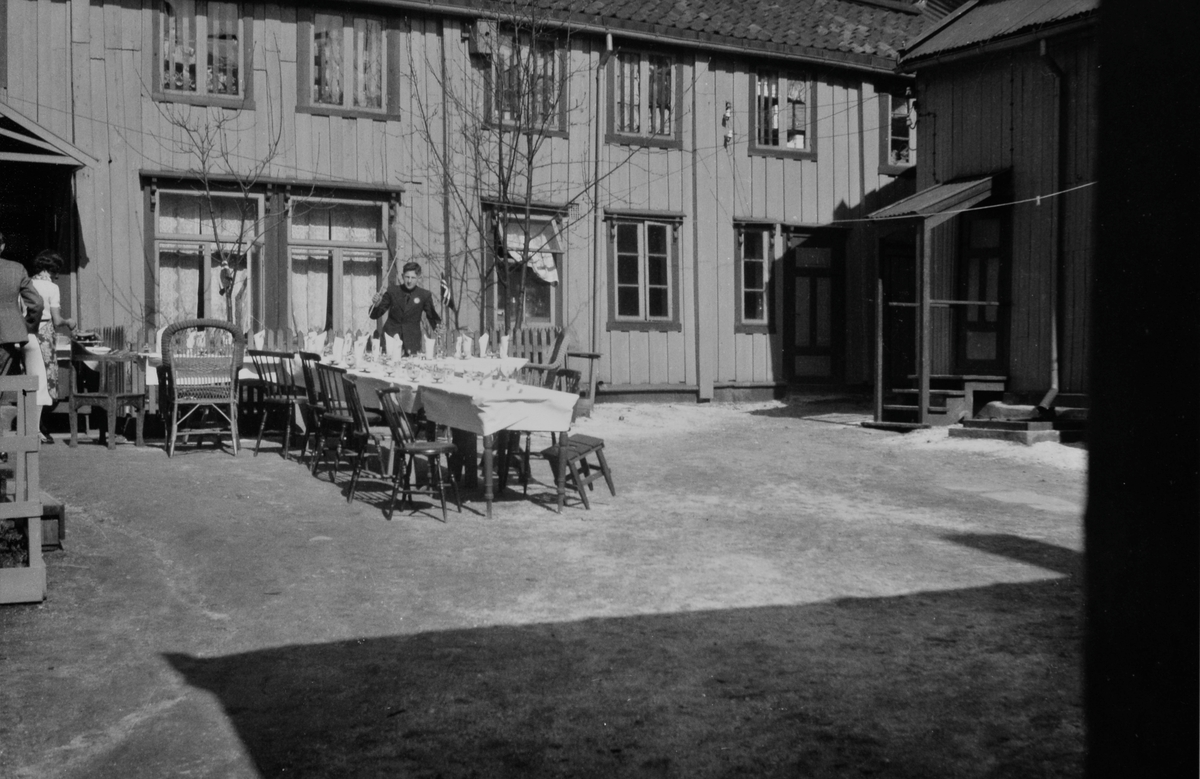 Hertze Caplan med flagg sto bak et dekket bord i Caplangården i Tromsø, 17.mai 1940.