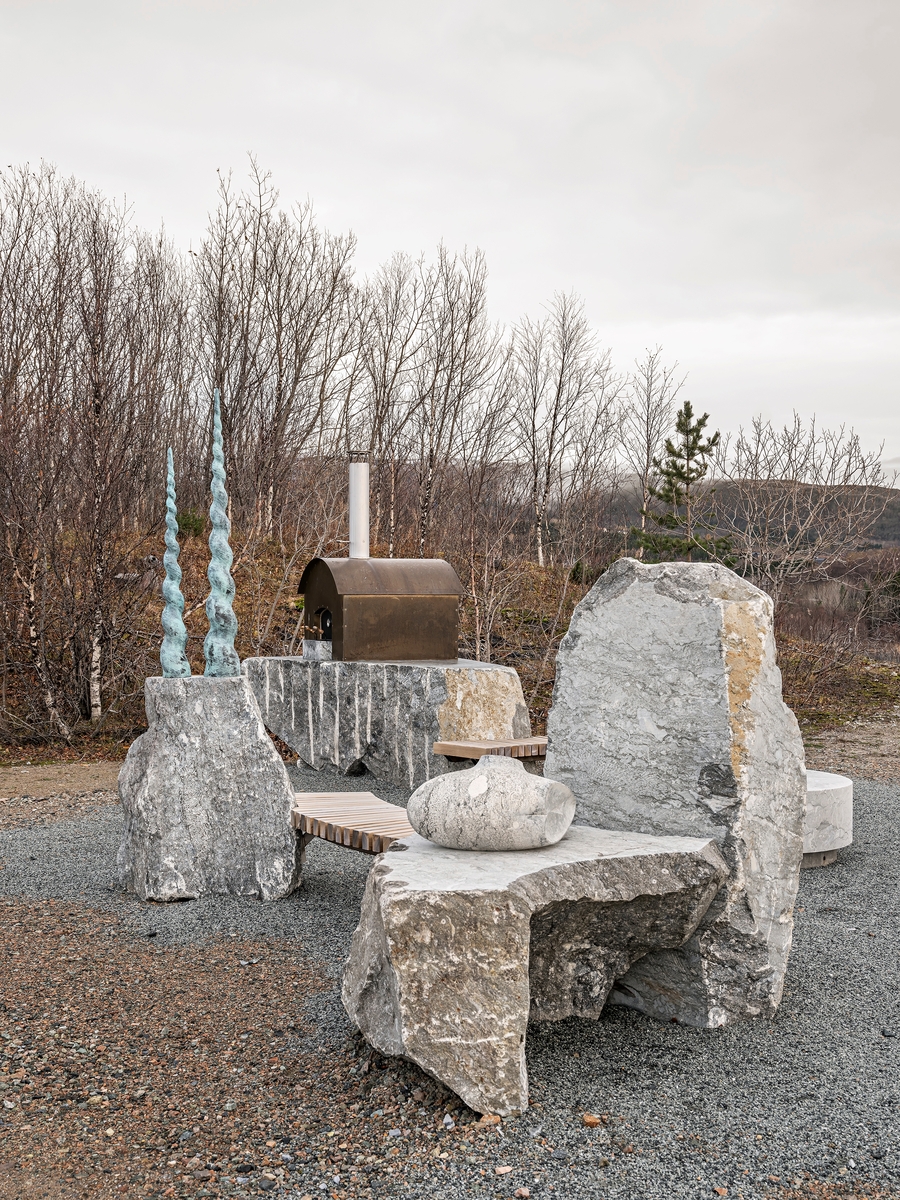 Bålet får folk til å komme sammen. Flammenes hypnotiske dans varmer, gir et felles fokus og får samtalen til å flyte av sted, mens røyksøylen stiger opp i nattehimmelen. I Verstos skulpturgruppe danner stein, bronseskulpturer, trebenker og en pizzaovn en åpen sirkel rundt bålplassen. Når går noe fra å være natur til å bli arkitektur? Skulpturene danner en bålplass, og en ramme for sosialt samvær. Mellom de grovhogde steinene dukker det opp raffinerte detaljer: Et dobbeltsneglehus, et hvilende hode, to spiralhorn, en krystallisk form og blikket fra en våkende rovfugl.