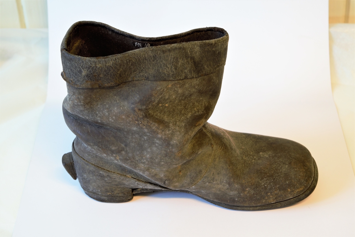 Lav lærstøvel til mann. Såle og hæl av flere lag lær. Øvre del sydd av tre lærstykker, dobbeltbrettet 4 cm bred kant øverst.