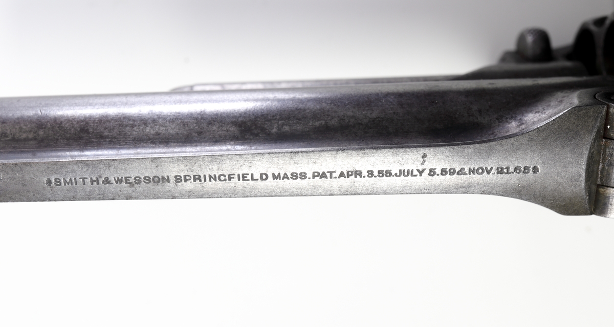 Revolver, Smith & Wesson, med trumma kamrad för fem patroner och räfflad pipa. Revolvern är enkelverkande, d.v.s. man måste spänna hanen manuellt innan skott kan avlossas. Plunderstock finns fast monterad under pipan, något som gör att man måste fälla upp pipan genom att lossa en spärr strax under trummans främre del, s.k. tip-up model. Därefter kan man, efter borttagande av trumman, trycka ut tomhylsorna. Sidoblecket är blånerat, och revolvern har en rundad kolv med kolvplattor av trä. Riktmedlen är fasta.
Inskrivet i huvudkatalogen 1971.