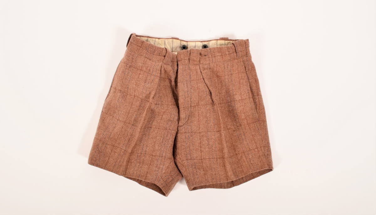 Dressbukse til gutt, mest sannsynlig i ullstoff. Mellombrun farge med vevde innslag av rødbrunt og mørkebrunt,  i tynne striper som utgjør et rutemønster. Baklomme på høgre side. Fôr i linningen og knapper for bukseseler på innsiden Tilhørende dressjakke og sokker/strømper har arkivnummer VFF 20770 og VFF 20772.