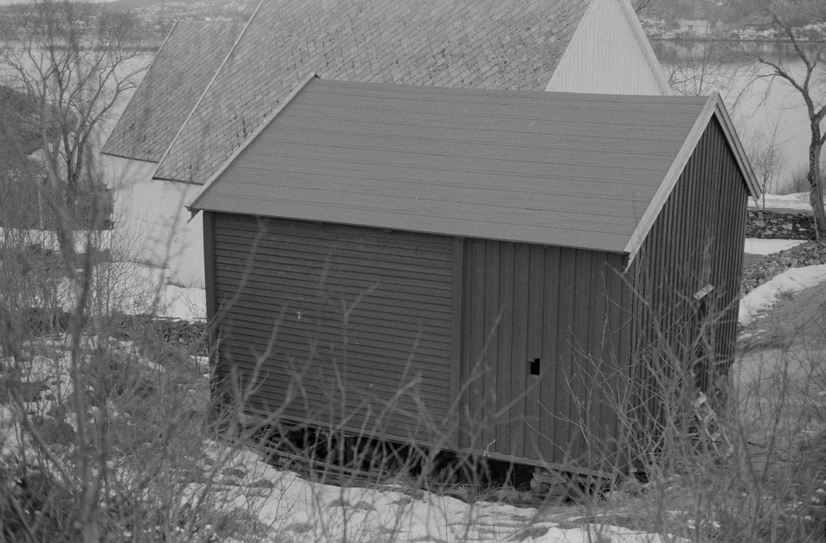 Stabburet på Dolm prestegård, Hitra, Dolm kirke i bakgrunnen.