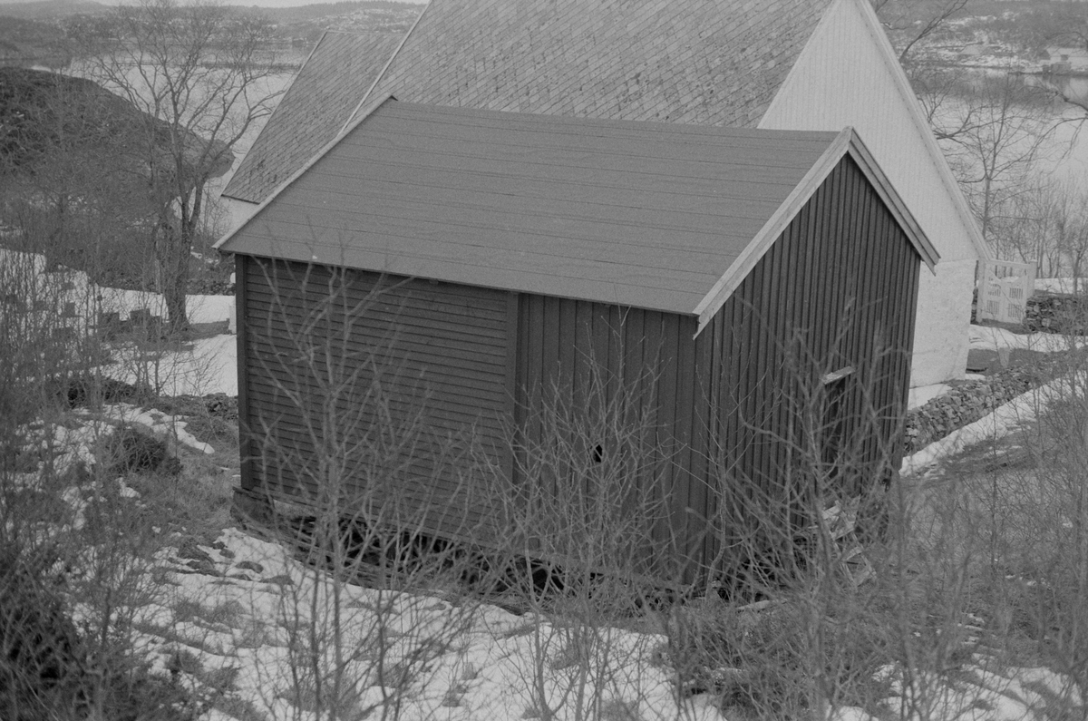 Stabburet på Dolm prestegård, Hitra, Dolm kirke i bakgrunnen.