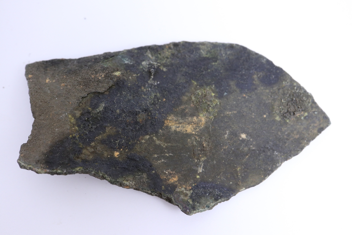 Brandskadat fragment av bronsgryta. Bukbit.