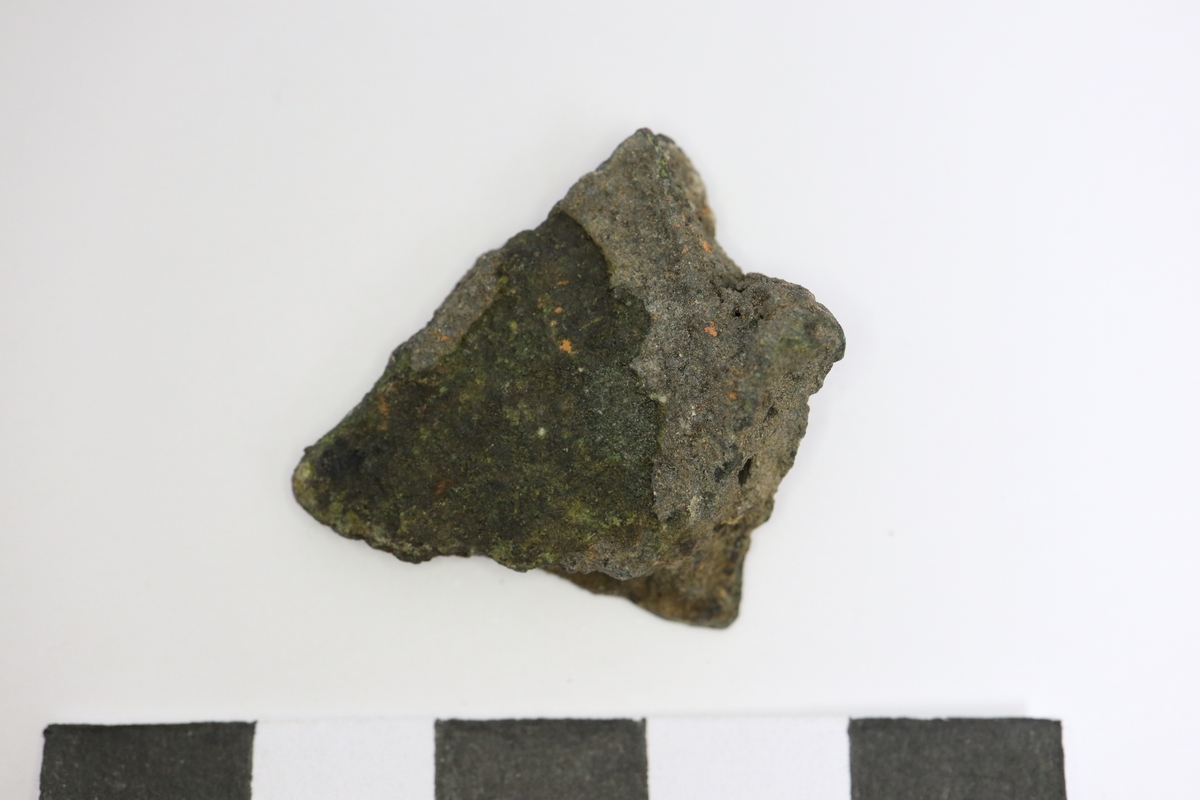 Brandskadat fragment av bronsgryta. Bukbit med eventuell skuldra.