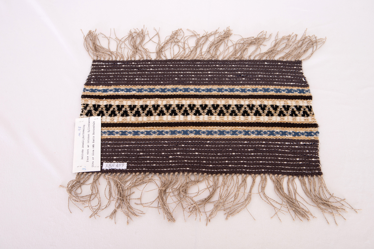 Provet har en maskinskriven papperslapp med texten: Nr 48, 3. Bollnäs Hemslöjdsförening. Prov vävt av  Bricken Gyllenhammar. Gåva av Elsa och Karin Nordenfelt.