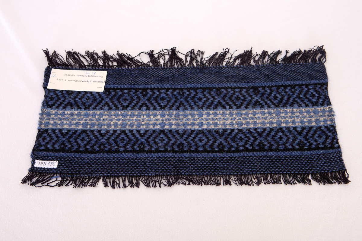 Provet har en påsydd bomullslapp med handskriven text: Bollnäs Hemslöjdsförening. 82. samt en maskinskriven papperslapp med texten: Nr 48, 16.Bollnäs Hemslöjdsförening.  Prov i rosengång. B. Gyllenhammar.