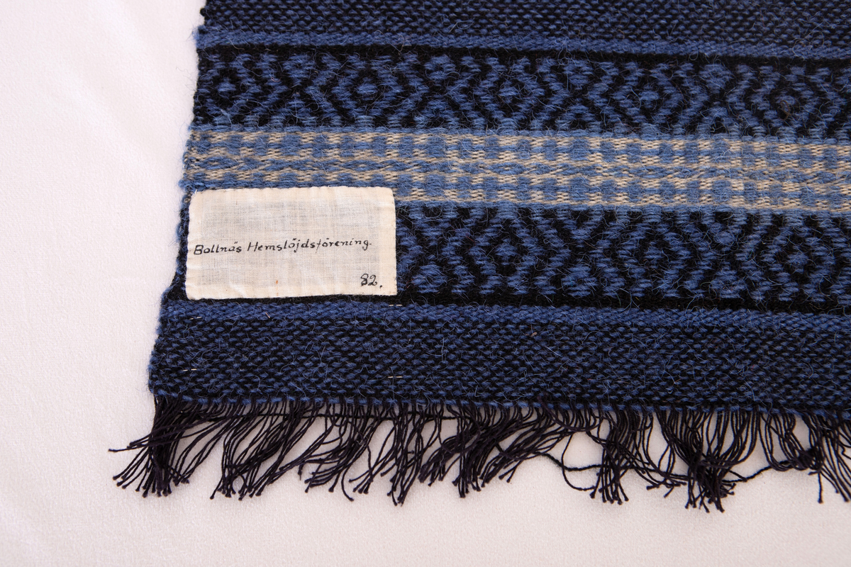 Provet har en påsydd bomullslapp med handskriven text: Bollnäs Hemslöjdsförening. 82. samt en maskinskriven papperslapp med texten: Nr 48, 16.Bollnäs Hemslöjdsförening.  Prov i rosengång. B. Gyllenhammar.