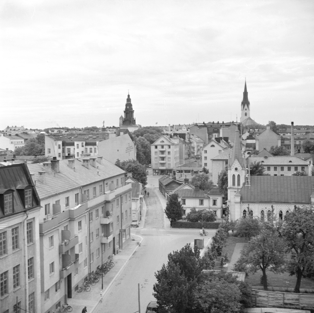 Vy utmed Ågatan i Linköping. Utsikt västerut från Hamngatan med delar av kvarteren Blåklockan och Bonden till vänster respektive höger närmast betraktaren. I bildens mitt korsas Ågatan av Snickaregatan med Metodistkyrkan (Emanuelskyrkan) som dominerande byggnad. Bortom kyrkan skymtar några av kvarteret Bokbindarens gamla trähus som inom kort kommer att rivas. Odaterad bild från tidigt 1950-tal.