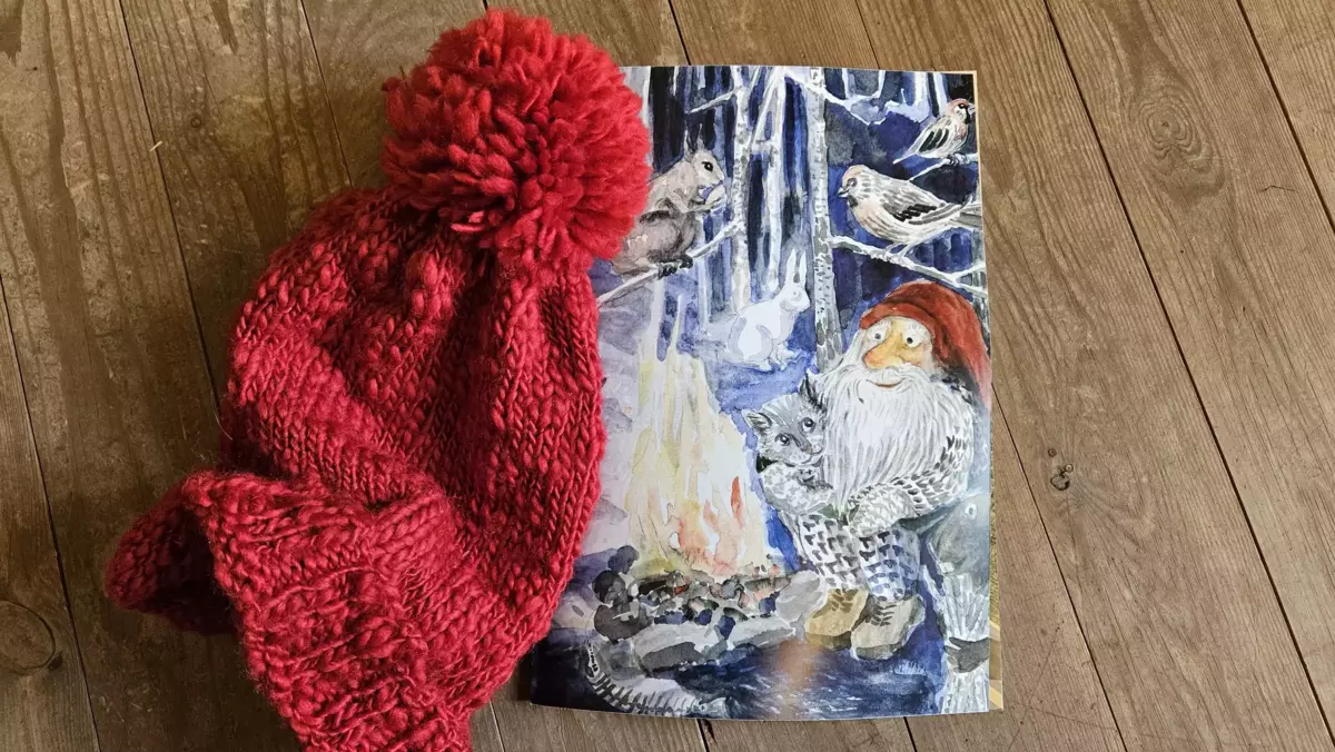 Foto av nisselue og postkort med nisse som sitter ved et bål.