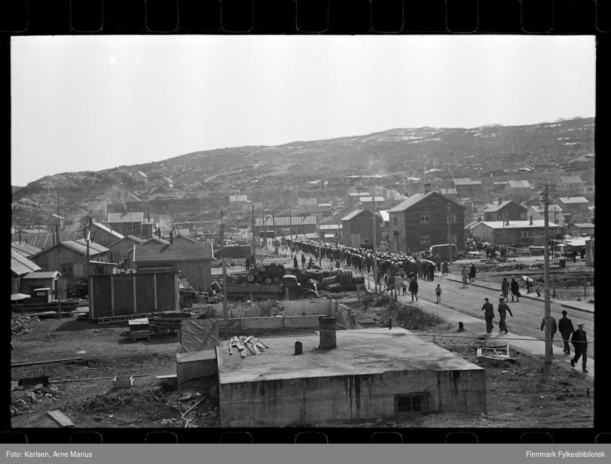 I pinsen (25-26.mai) 1947 ble det avholdt sangerstevne i Kirkenes, der folk kom med huritgruten fra Båtsfjord, Vardø, Vadsø og Honningsvåg. Foto antagelig tatt i denne anledning

Mannskor marsjerer i parade langs gate i Kirkenes. I forgrunnen kan man se en grunnmur 