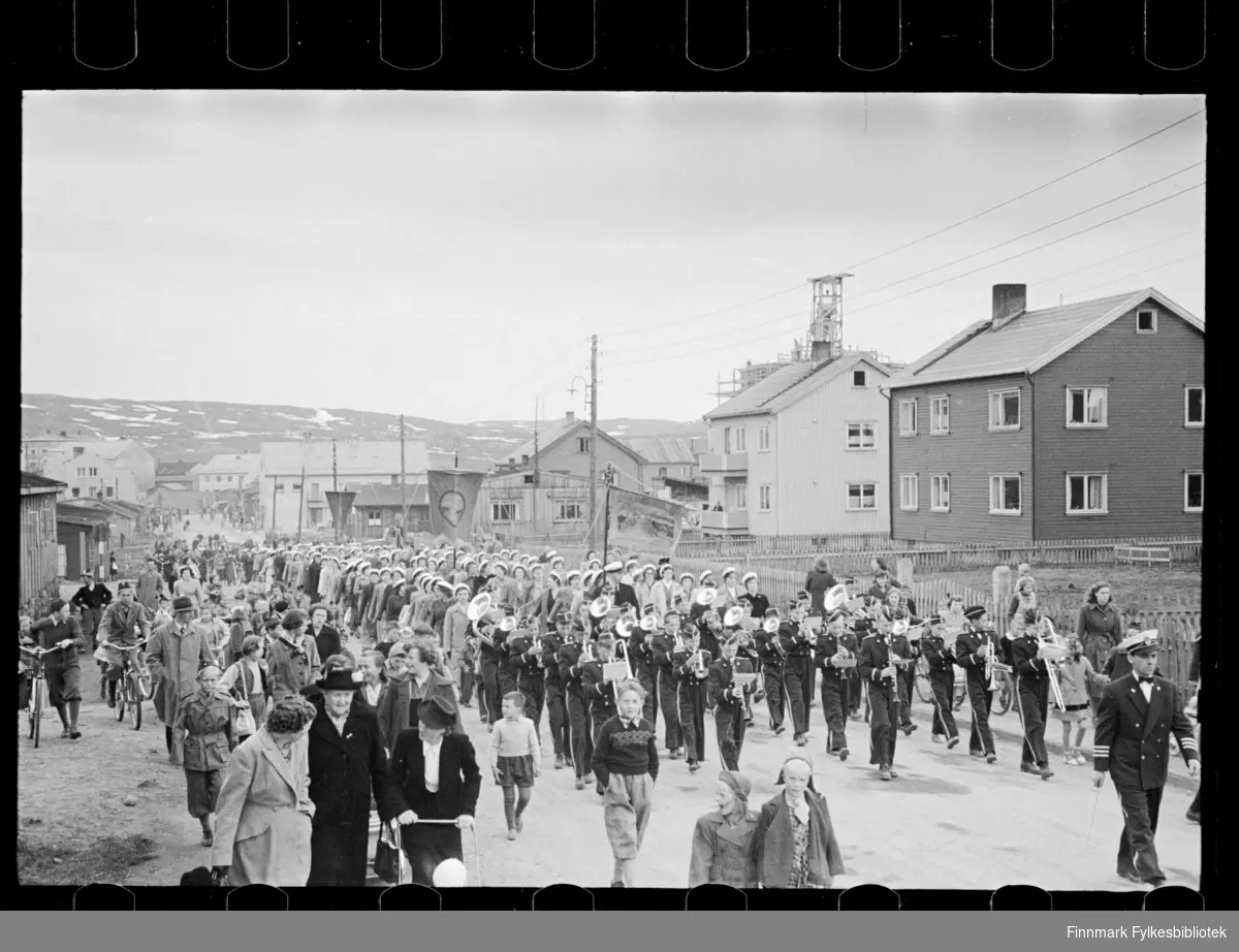 Trolig sangstevne i Kirkenes pinsen 1947 (25 -26 mai), deltakerne har samlet seg til opptog. På det framste banneret i toget står det: Syng deg fram (synes i andre foto i serien)

Sangere fra hele Finnmark samlet seg til stevne i Kirkenes, der i blant fra Båtsfjord, Vardø, Vadsø og Honningsvåg