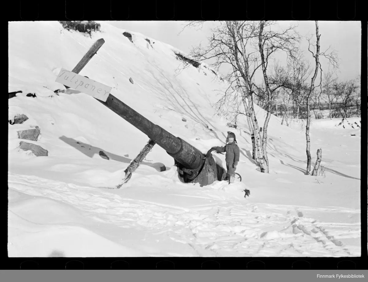 Foto av nedsnedd maskineri med skilt på. Ruiner av kanon?  På skiltet står det "Tulipaner"  og en liten gutt står ved siden av. 

Muligens tatt i 1947 (se historikk)

Foto trolig tatt på slutten av 1940-tallet, eller tidlig 1950-tallet