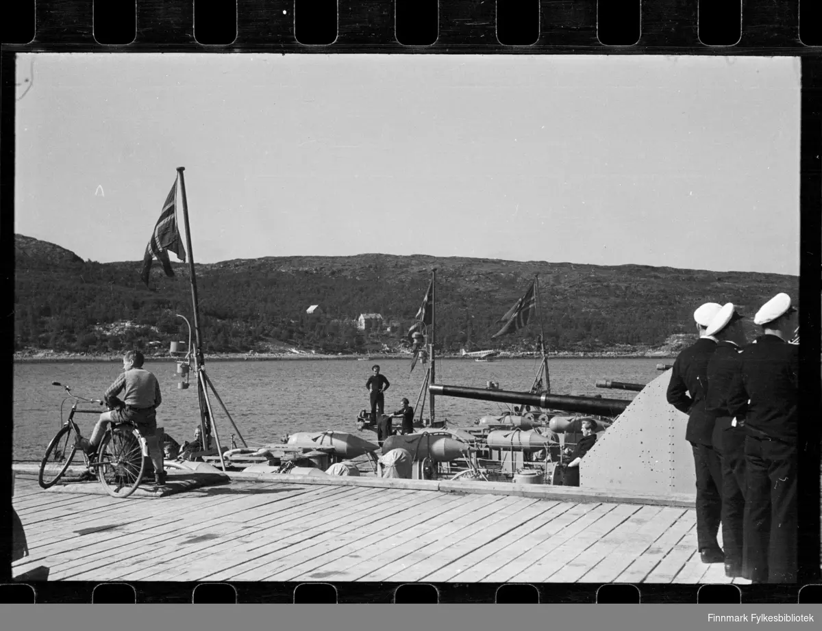 Foto av krigsskip i Kirkenes

En gutt sitter på sykkel til venstre

Til høyre kan man se offiserer 

Foto trolig tatt på slutten av 1940-tallet, eller tidlig 1950-tallet