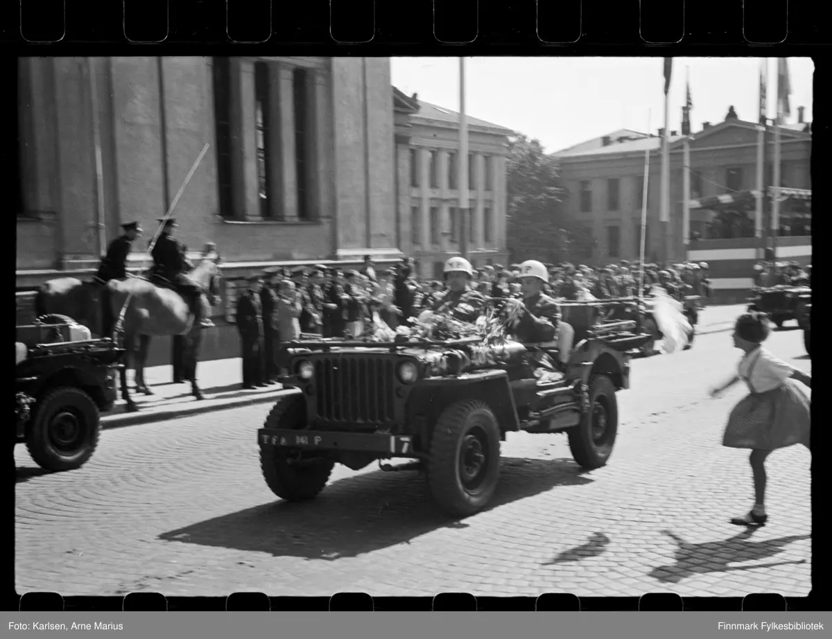 Foto av og amerikansk militær politi i hvit hjelm (US Military Police Corps) kjørende i Jeeps langs Karl Johangate på vei mot slottet. Foto tatt på de alliertes dag den 30 juni 1945 (The Allied Forces day)

Bilene er av modell Willys MB/Willys Jeep

I bakgrunnen til høyre kan man se en tribune der flere offiserer står som tilskuere (synes bedre i andre foto i serien)