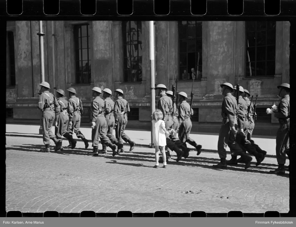 Britiske soldater marsjerer i parade på de alliertes dag den 30. juni 1945 (The Allied Forces day)

Et barn har sprunget opp til soldatene for å rekke de blomster. Flere av soldatene bærer allerede på små buketter 