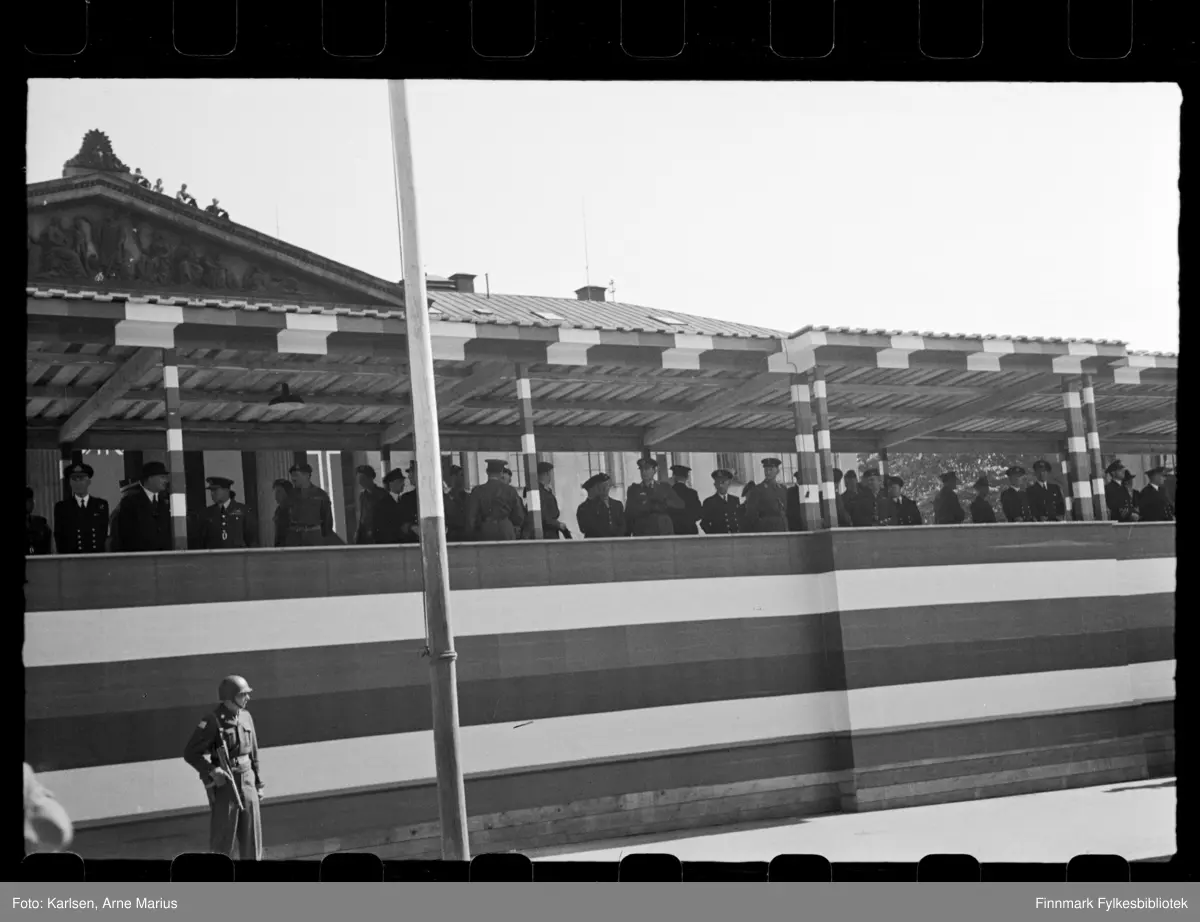 Foto av offiserer på tribune med oversikt over militærparaden på de alliertes dag den 30. juni 1945 (The Allied Forces day)

Blant de avbildete er trolig norske, britiske og muligens amerikanske offiserer. I bakgrunnen kan man se Universitetsplassen
