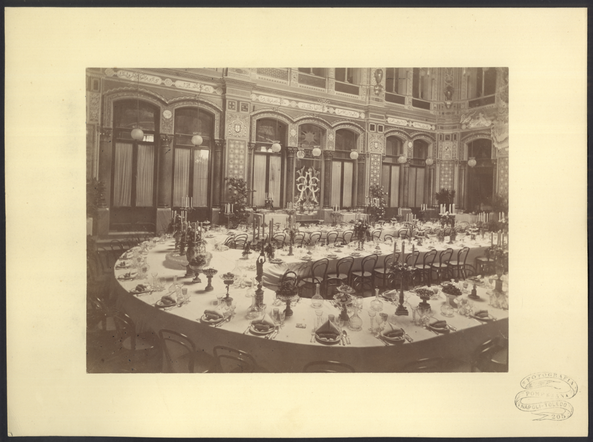 Bilden visar matsalen på det italienska geografiska sällskapet som är dukat för en festlig middag för Vegaexpeditionens medlemmar. Sittmöblen är i hela salen är Thonets berömda "Konsumstuhl Nr. 14".