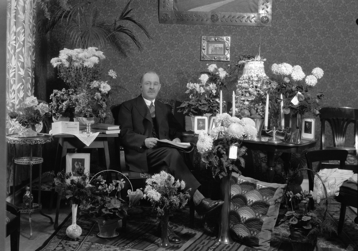 Porträtt. Man sittandes vid blomsterbord.