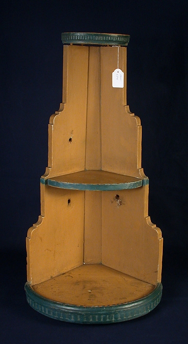 Hörnhylla i trä. Gulmålad, tre hyllor blåmålade. Mått: Hyllornas diameter: 1: 140mm. 2: 170mm. 3: 310mm.
