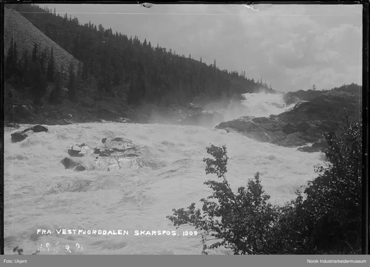 Elva mellom Skarfoss og Rjukanfossen. Steintipp i fjellsiden på oversiden av elva.