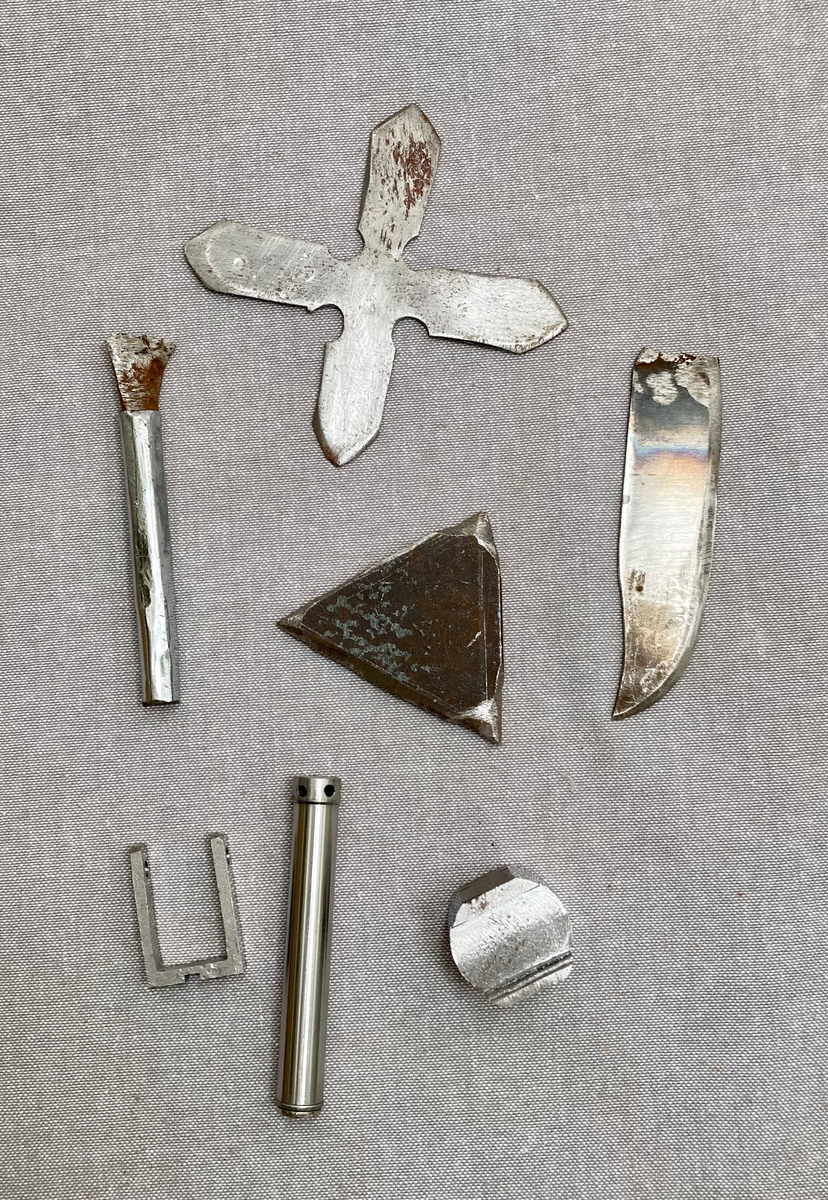 Hjemmelagede våpen, kastestjerne, knokejern, to pistoler og deler til en tredje, kølle med fjering, en hjemmelaget nøkkel, diverse hjemmelagde knivblad.