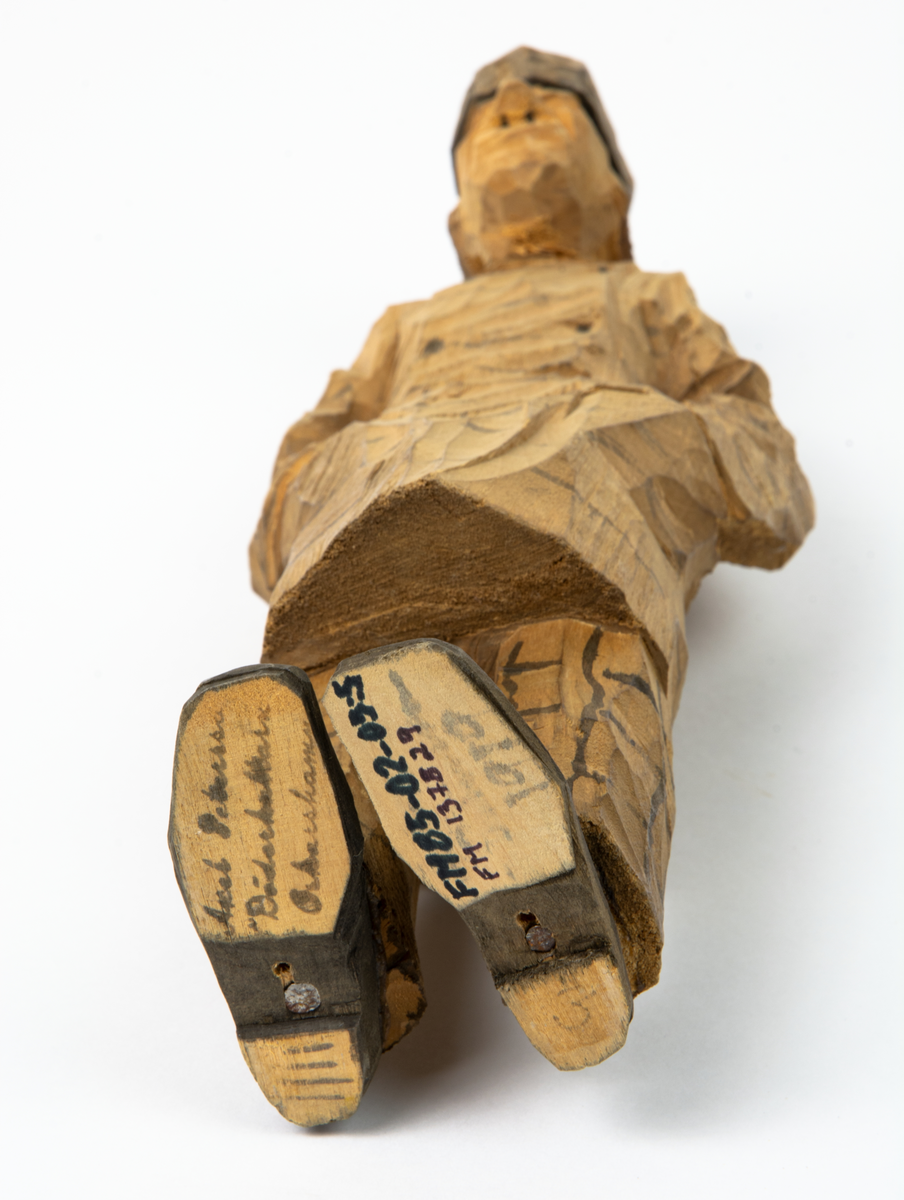 Auktion, skulpturgrupp föreställande sex personer som lyssnar till en auktionist. 
Figurer:
1. Man med händerna i fickorna, randig rock och rutiga byxor, pälsmössa. H 282 mm. 
2. Man med rock och pälsmössa. H 283 mm. 
3. Man med hatt och rock. I handen håller han ett par stövlar, H 274 mm. 
4. Kvinna insvept i schal. Hon håller ett klädesplagg, l 268 mm. 
5. Kvinna med schal och lång kjol. Hon håller ett klädesplagg, H 264 mm.
6. Kvinna insvept i schal.
7. Auktionist, "Ropar-Olle", som håller upp en potta. Den andra handen håller en klubba. Han står på en upp och nedvänd tunna.