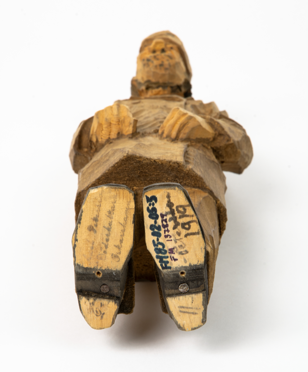Auktion, skulpturgrupp föreställande sex personer som lyssnar till en auktionist. 
Figurer:
1. Man med händerna i fickorna, randig rock och rutiga byxor, pälsmössa. H 282 mm. 
2. Man med rock och pälsmössa. H 283 mm. 
3. Man med hatt och rock. I handen håller han ett par stövlar, H 274 mm. 
4. Kvinna insvept i schal. Hon håller ett klädesplagg, l 268 mm. 
5. Kvinna med schal och lång kjol. Hon håller ett klädesplagg, H 264 mm.
6. Kvinna insvept i schal.
7. Auktionist, "Ropar-Olle", som håller upp en potta. Den andra handen håller en klubba. Han står på en upp och nedvänd tunna.