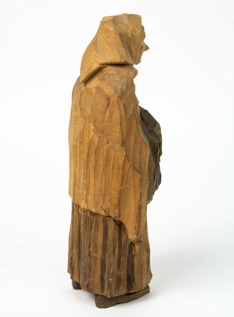 Auktion, skulpturgrupp föreställande sex personer som lyssnar till en auktionist. 
Figurer:
1. Man med händerna i fickorna, randig rock och rutiga byxor, pälsmössa. H 282 mm. 
2. Man med rock och pälsmössa. H 283 mm. 
3. Man med hatt och rock. I handen håller han ett par stövlar, H 274 mm. 
4. Kvinna insvept i schal. Hon håller ett klädesplagg, l 268 mm. 
5. Kvinna med schal och lång kjol. Hon håller ett klädesplagg, H 264 mm.
6. Kvinna insvept i schal.
7. Auktionist, "Ropar-Olle", som håller upp en potta. Den andra handen håller en klubba. Han står på en upp och nedvänd tunna.
