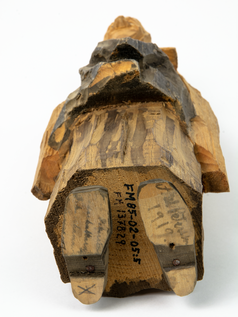 Auktion, skulpturgrupp föreställande sex personer som lyssnar till en auktionist. 
Figurer:
1. Man med händerna i fickorna, randig rock och rutiga byxor, pälsmössa. H 282 mm. 
2. Man med rock och pälsmössa. H 283 mm. 
3. Man med hatt och rock. I handen håller han ett par stövlar, H 274 mm. 
4. Kvinna insvept i schal. Hon håller ett klädesplagg, l 268 mm. 
5. Kvinna med schal och lång kjol. Hon håller ett klädesplagg, H 264 mm.
6. Kvinna insvept i schal.
7. Auktionist, "Ropar-Olle", som håller upp en potta. Den andra handen håller en klubba. Han står på en upp och nedvänd tunna.