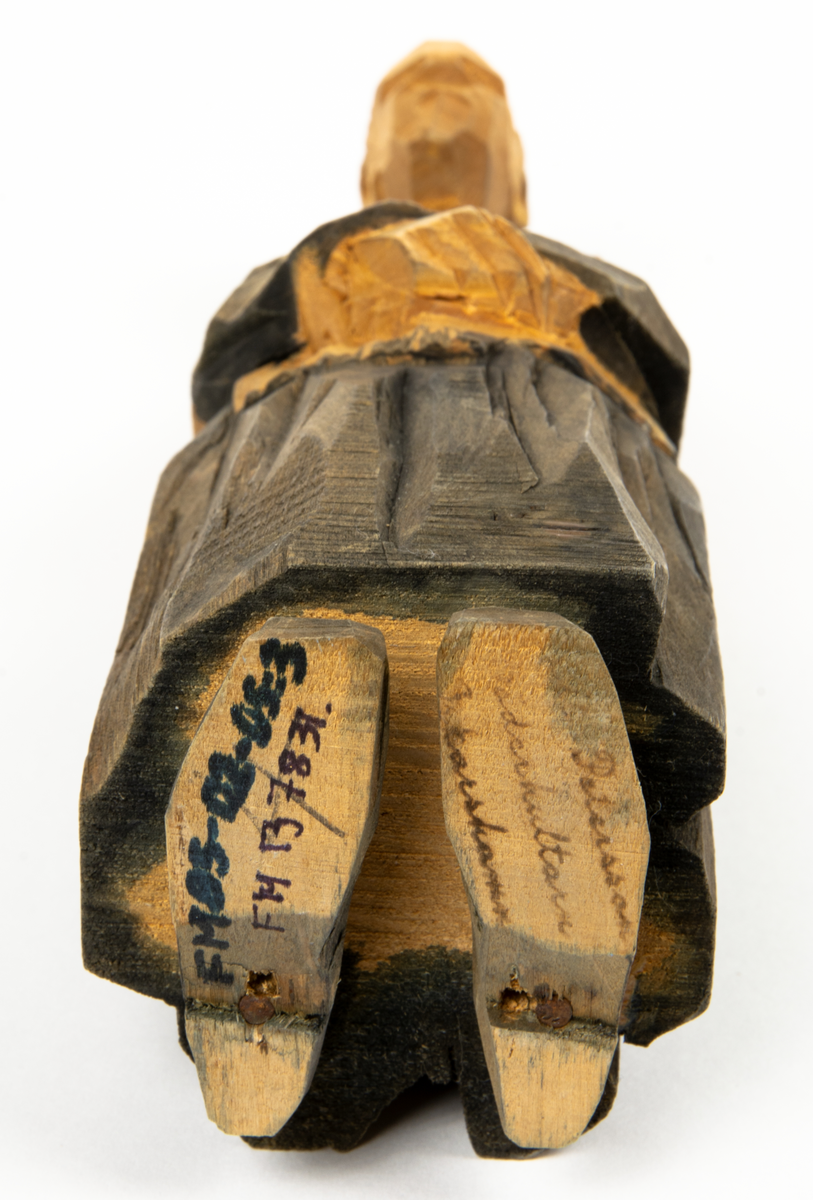 Bröllop, grupp med träskulpturer föreställande ett brudpar framför en präst samt två vittnen. 
Figurer: 
1. Präst i svart rock. Han håller en bok i ena handen. H 235 mm. 
2. Brudgum i svart frack. H 232 mm. 
3. Brud i svart klänning och vit slöja och en stor blombukett. H 214 mm. 
4. Bröllopsvittne. Äldre man i svart rock. H 210 mm. 
5. Bröllopsvittne, äldre kvinna isvart klänning och schal. H 218 mm.