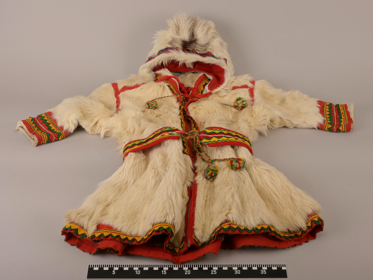 Pesk av pels skinn med lue og belte. Pesken har strammebånd rundt halsen og glidelås til gjenknepping. Skinnet er av enten kalv eller geit. Hårene er for mjuke og ikke hule, slik voksne reinsdyr har. På ryggen av pesken er skinnet strammet inn og her er innfelt røde bånd som fungerer som dekorering. Pesken er foret med rødrutet for.
Luen er av reinsdyrskinn. Beltet er av bomull.