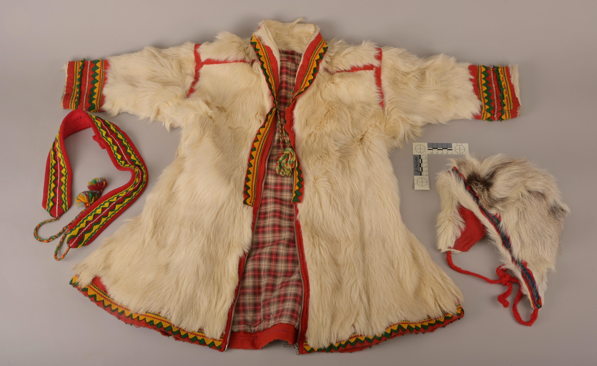 Pesk av pels skinn med lue og belte. Pesken har strammebånd rundt halsen og glidelås til gjenknepping. Skinnet er av enten kalv eller geit. Hårene er for mjuke og ikke hule, slik voksne reinsdyr har. På ryggen av pesken er skinnet strammet inn og her er innfelt røde bånd som fungerer som dekorering. Pesken er foret med rødrutet for.
Luen er av reinsdyrskinn. Beltet er av bomull.