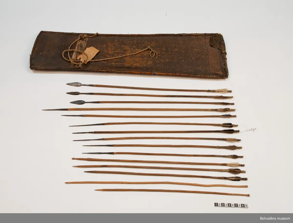 Ur handskrivna katalogen 1957-1958:
Pilkorger m. 15 pilar; Afrika.
Kogret a) L. 75 Br 22 cm.
flätat av tunna vidjor; förstärkt på 2 ställen m. skinn, flätad snodd att bära i. Ngt. trasigt. 
Samtliga pilar har runda träskaft  och har styrfjädrar, utom. o och p;
b-d, L.60,9; 60,5; 58,8 cm. m. lansettform. järnspetsar m. holk.
e-k, L. 68,5; 61,4; 58,2; 56,8; 56,3; 53,0; 53,0; m.långsmala 4- kantiga pikar i spetsen, m. holk.
L-p, L. 56; 55,5; 51,8; 57,4; 47,7 cm. dessa 5 har endast träskaftet tillskuret som spets.
L-o m. hullingar.
(o och p är ofjädrade, se ovan!). De flesta pilarna något skamfilade.

Lappkatalog: 9
