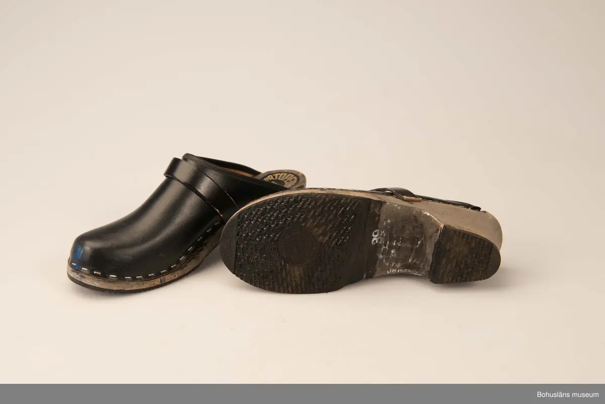Storlek 39. Ortopediska. Svensk tillverkning. Svartbetsad träsula, svart ovanläder. 
Använda av sillskärerskor vid ABBA konservfabrik i Lysekil.