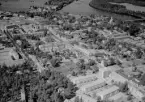 Flygfoto över Avesta 1965. Corneliusgatan med stadshus, stadshusparken och vattentornet med Karlbergsarken i förgrunden. Kungsgatan med Avesta bryggeri och Epa-varuhus. Avesta kyrka. Koppardalen, gamla byn.
