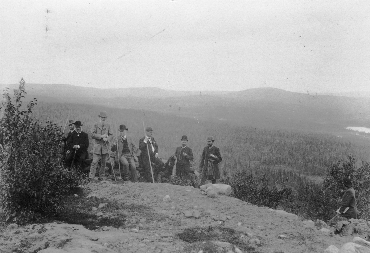 Fotografi från samlingen Gellivararesan 1890. Text på baksidan: Gellivara. Herrlig utsikt från Tingsvalla. Snöfjäll synliga vesterut på 16 mils afstånd, bland dem Sveriges högsta bergstopp Kebnekaise. Staffage: Swedelius, Hummel, Sjögren, Lundström, Lundeberg, de Laval och Lundbom.