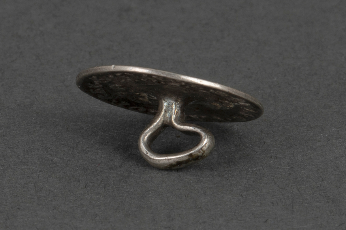 Tolv like støpte knapper i sølv. Knappene er runde, lavt hvelvede og har en fast bøyle på baksiden. På forsiden i relieff: kongeportrett i profil og omskrift "FRID. IIII: (på én knapp FRID IV) DEI. GRANT. På baksiden: Krone og omskrift "DAN. NOR. VAN. GOT. REX., samt 8 S, D. M. A." og forskjellige årstall "1702, 1703 (to ganger), 1704 (to ganger), 1705, 1707, 1709, 1712, 1713 (to ganger), og 1714". Knappene er laget av mynter (8 skilling).