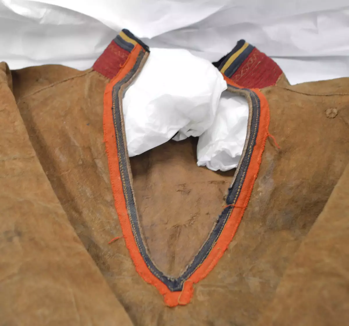 Sválltjá/kinnkofte med tekstilapplikasjoner og grindvevd pyntebånd. Goahkka/Krage i vinrød bunnfarge, uten divlle, men dekor øverst i grønt og gult. Badjelbuttas i goahkka/krage er mørkeblå. Åhtså med sájá i rødt og blått. Sase/ermedekor med sájá i blått og rødt og med badjelbuttas i brunt skinn. Nederst påsydd snjisjkodum/vevd lissto/kantband.