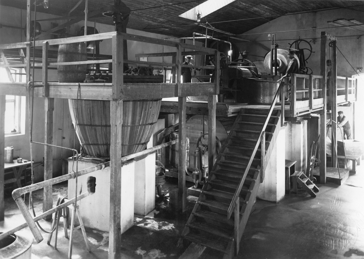 AB Bofors Nobelkrut. Malning av bomullskrut (nitrocellulosa). På läktaren till höger står två så kallade holländare av samma typ som användes vid pappersbruken. Till vänster en kokare för särskilda experiment. 1905.