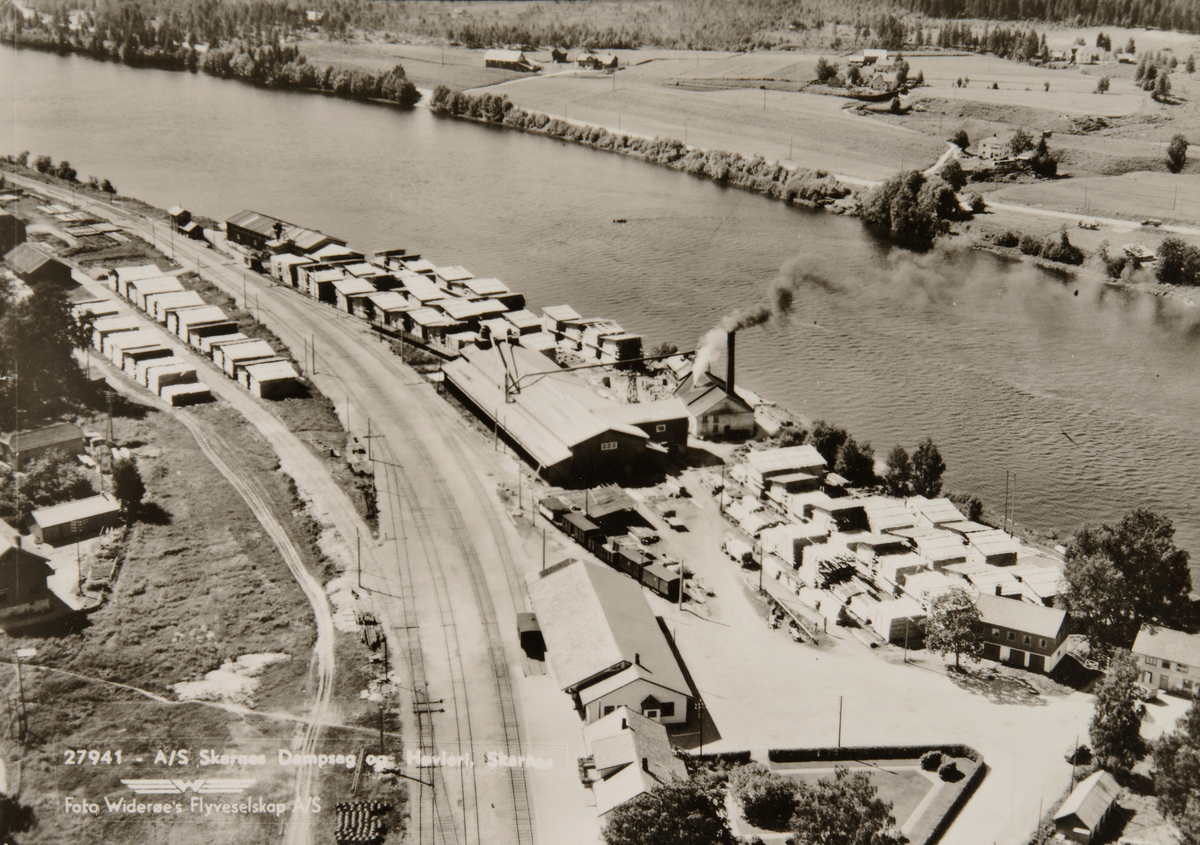 Postkort, Skarnes stasjon, flyfoto, jernbanestasjon, stasjonsbygning, jernbanespor, Skarnes dampsag & Høvleri, Glomma,