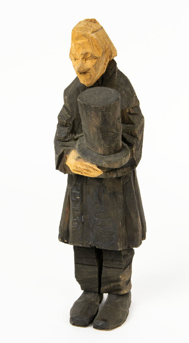 Skulpturgrupp "Begravningen", bestående av 8 objekt föreställande 6 män en präst, en kvinna samt en kista på bockar. 
Gruppens figurer: 
1. Dödgrävare Hultgren i rock och med hatt i handen. H 256 mm.
2. Svartklädd bärare som håller en hatt. H 234 mm. 
3. Svartklädd bärare som håller en hatt. H 240 mm. 
4. Svartklädd bärare som håller en hatt. H 140 mm. 
5. Klockare Sjöström som håller en hatt. H 265 mm.
6. Prosten Arbman med mantelsläpet runt ena armen. I vänstra hande håller han en uppslagen bibel och i den andra skall han hålla en skopa (vilken saknas). H 272 mm.
7. Den sörjande änka i svart klänning och schal och vit näsduk. H 238 mm.
8. En kista på två bockar, L 290 mm.